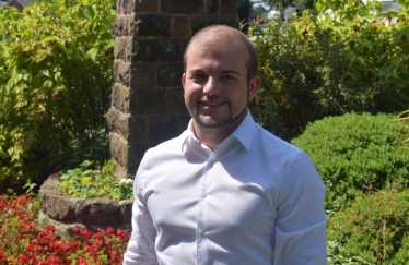 Picture of Zachary Collingham in front of greenery.